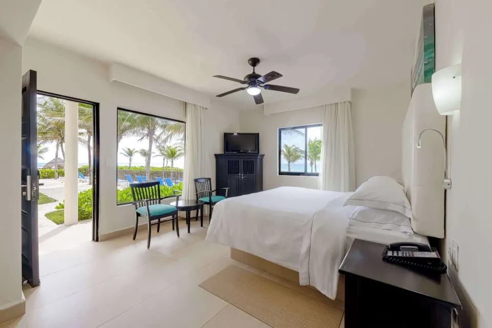 Premium Room with king bed, open door, seating area, TV cabinet, and poolside view at Allegro Playacar.