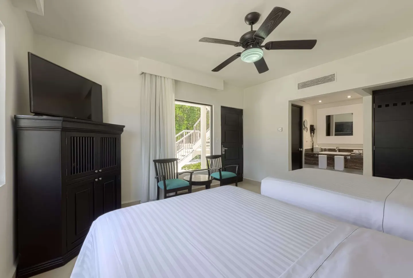 Superior Room king bed with TV cabinet, chairs, and open door at Allegro Playacar.