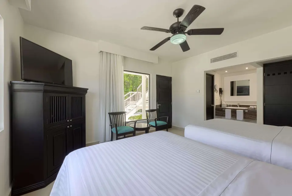 Superior Room king bed with TV cabinet, chairs, and open door at Allegro Playacar.