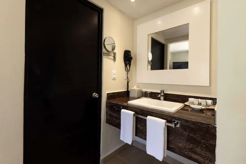 Superior Room vanity with sink, towels, mirror, and hair dryer at Allegro Playacar.