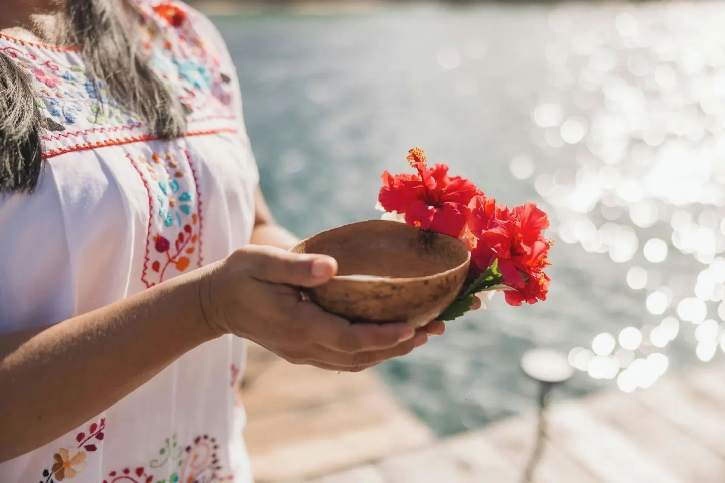 A person holds a coconut bowl with red hibiscus flowers at Almare, a Luxury Collection Resort, Isla Mujeres.