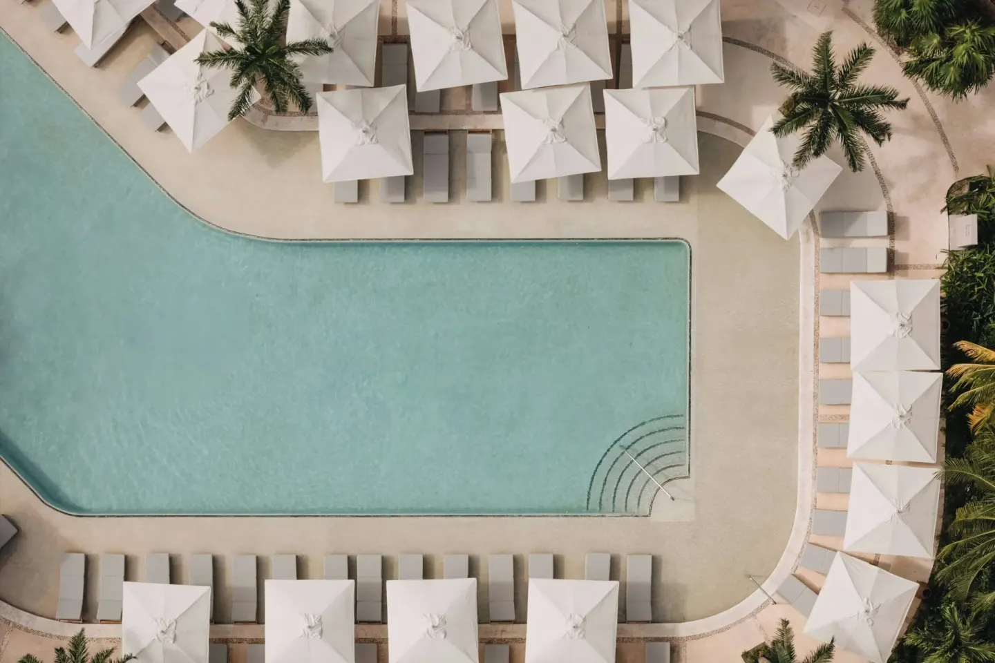 Aerial view of the main pool with umbrellas and palm trees at Almare, a Luxury Collection Resort, Isla Mujeres.