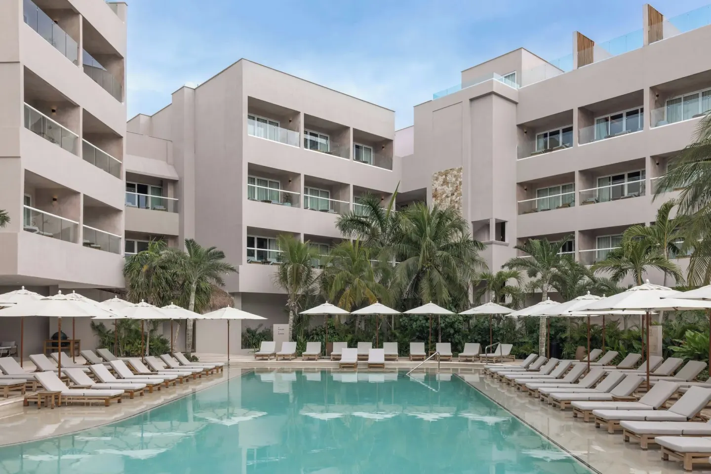 Main pool courtyard with balconies and rows of loungers at Almare, a Luxury Collection Resort, Isla Mujeres.