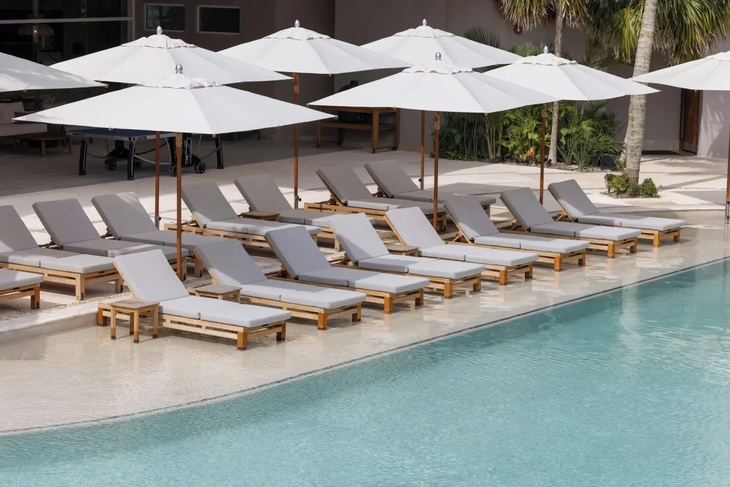 Rows of cushioned pool loungers under white umbrellas at Almare, a Luxury Collection Resort, Isla Mujeres.