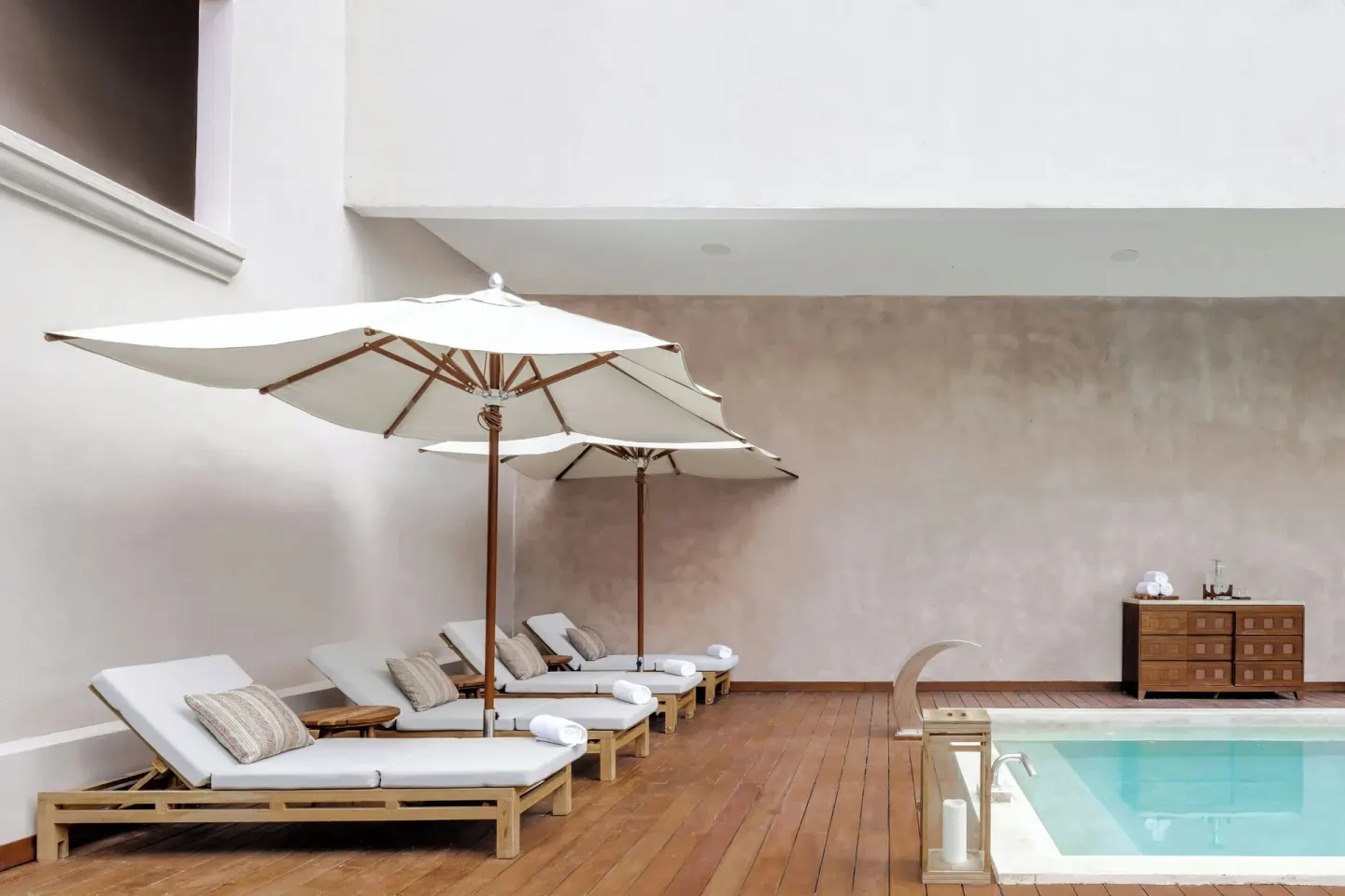Pool loungers with white umbrellas line a wood deck at Almare, a Luxury Collection Resort, Isla Mujeres.