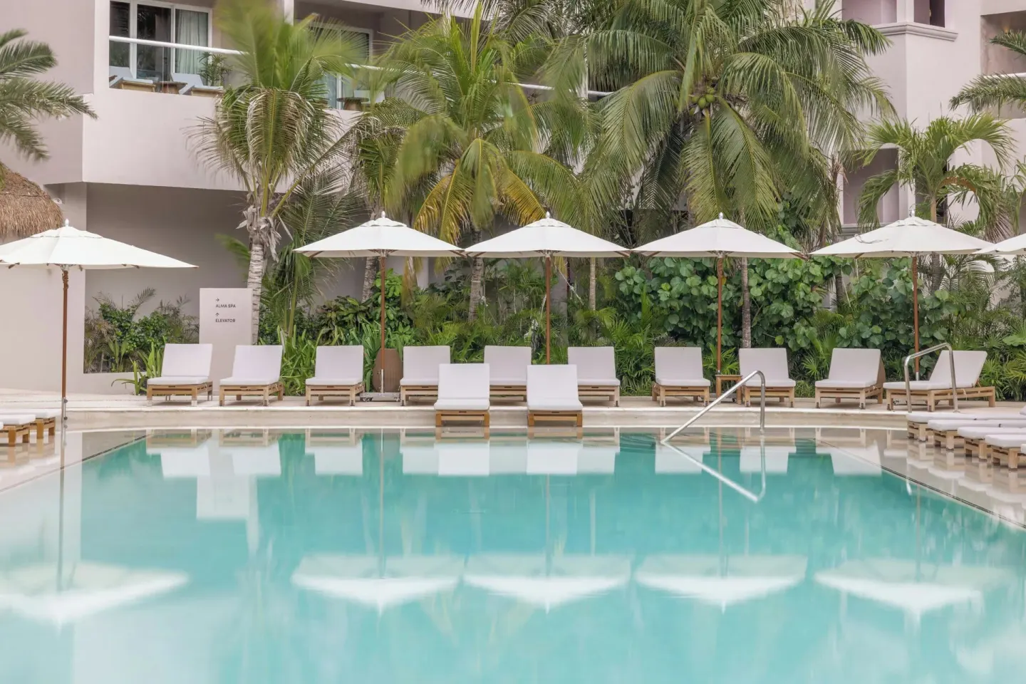 White loungers and umbrellas reflected in the pool at Almare, a Luxury Collection Resort, Isla Mujeres.