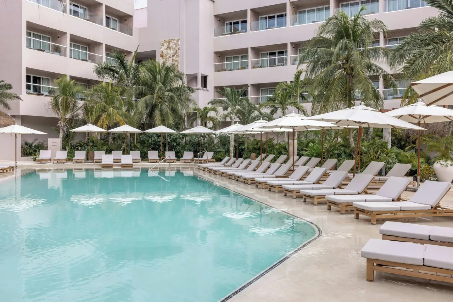Poolside loungers and umbrellas beside guestroom balconies at Almare, a Luxury Collection Resort, Isla Mujeres.
