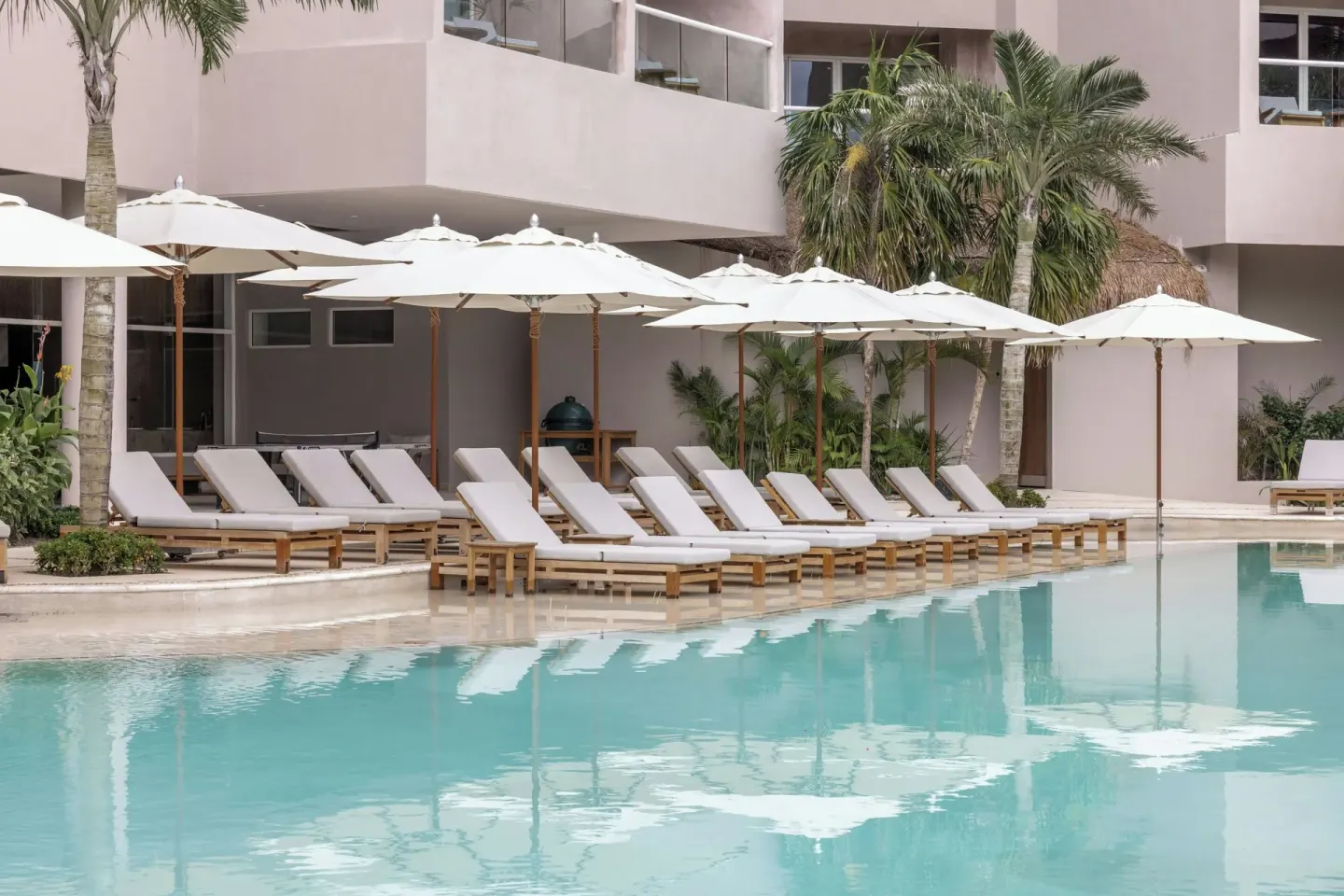 Pool loungers and white umbrellas beside the water at Almare, a Luxury Collection Resort, Isla Mujeres.