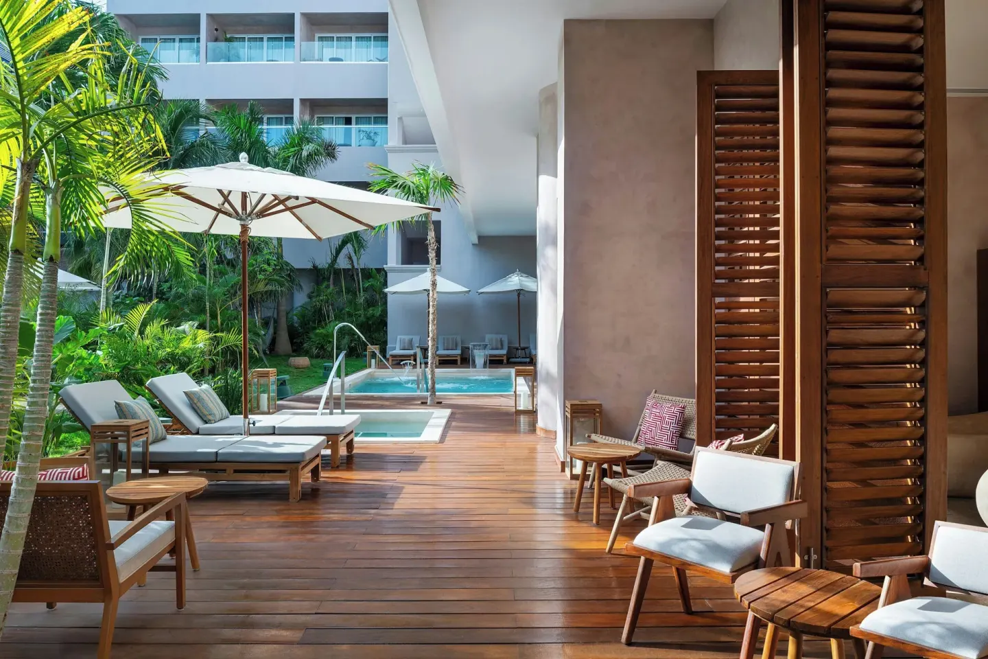 A shaded pool deck with loungers and palms is shown at Almare, a Luxury Collection Resort, Isla Mujeres.