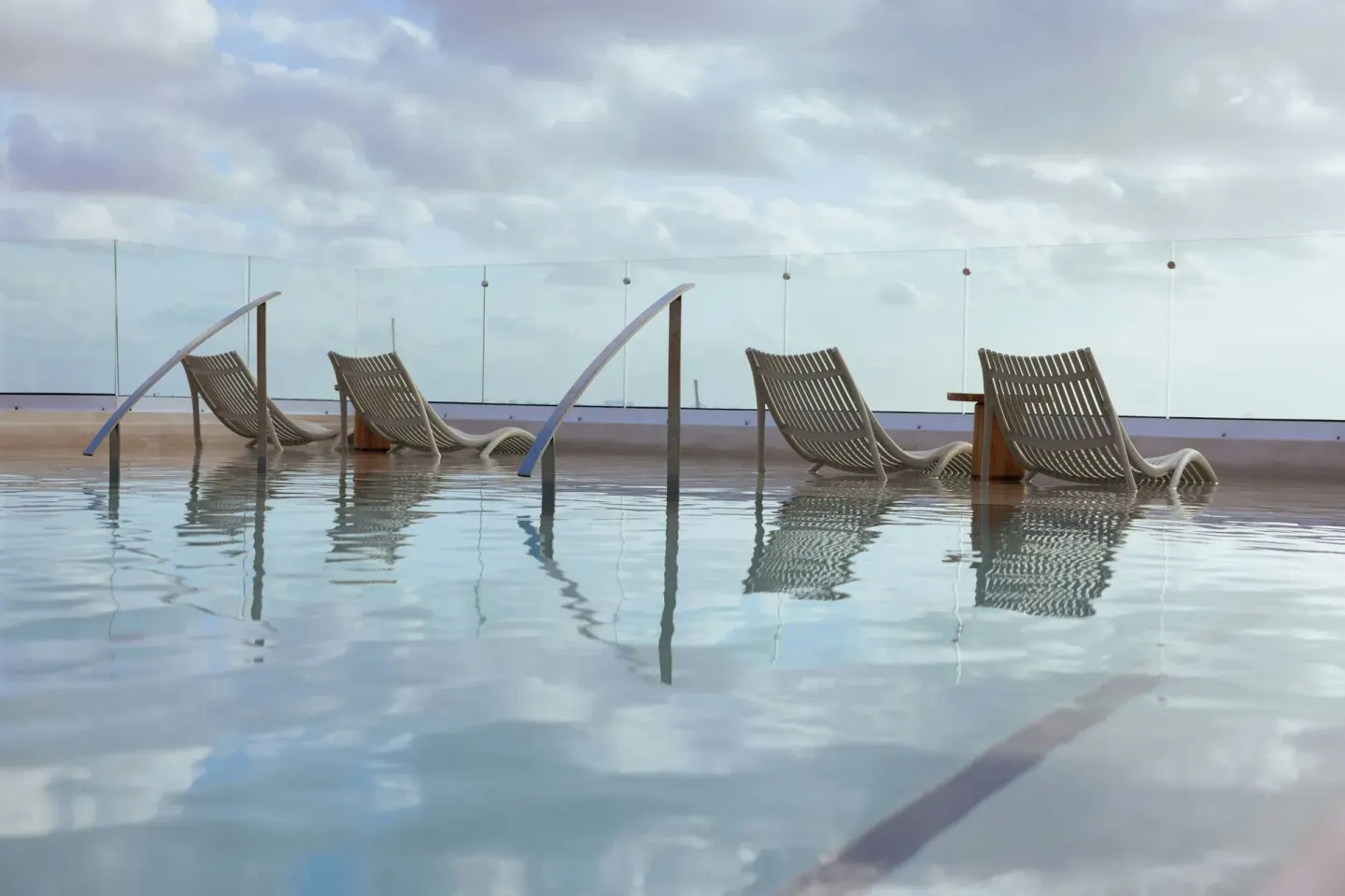 Shallow pool loungers and glass railing overlooking the horizon at Almare, a Luxury Collection Resort, Isla Mujeres.