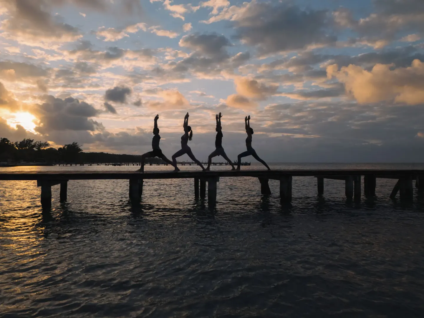 Four people pose on a pier at sunset over the water at Almare, a Luxury Collection Resort, Isla Mujeres.