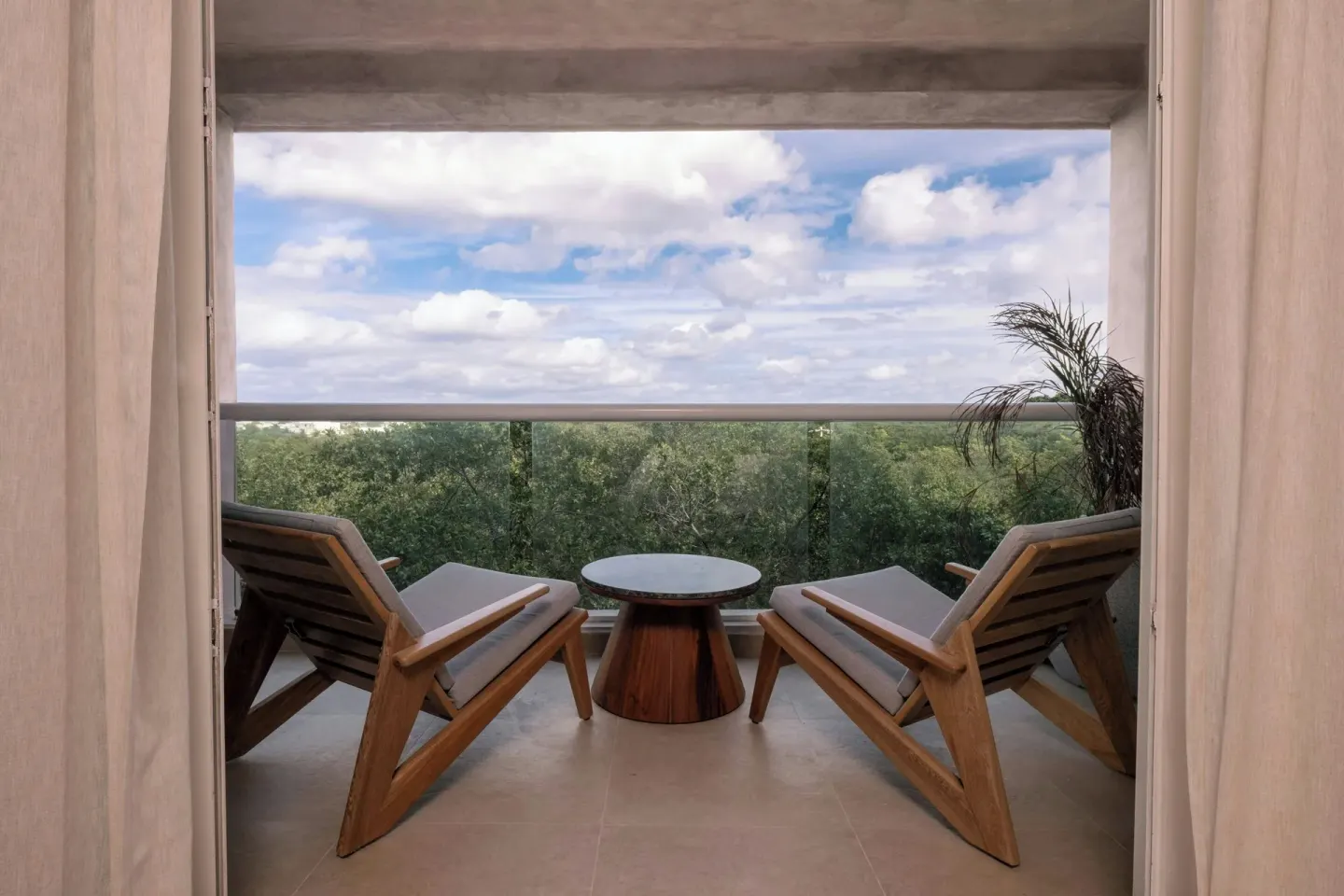 Standard Room Balcony seating with glass railing and treetop view at Almare, Isla Mujeres.