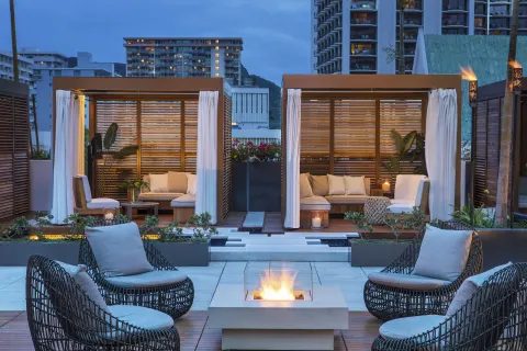 Private-style cabanas and fire feature at 'Alohilani Resort Waikiki Beach.