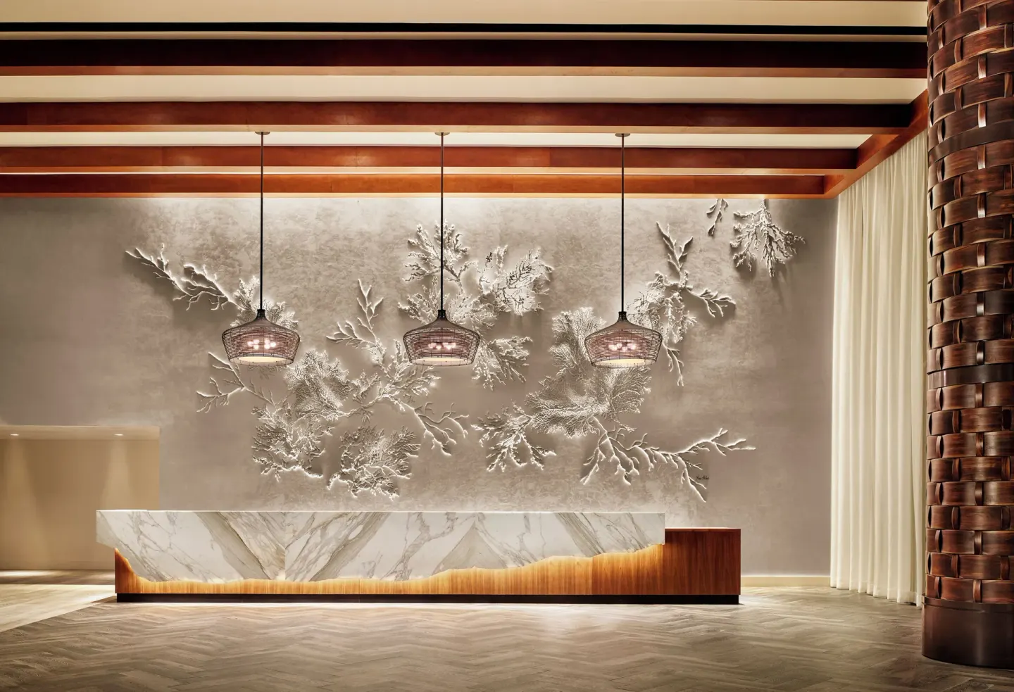 Lobby reception desk with coral wall art at 'Alohilani Resort Waikiki Beach.