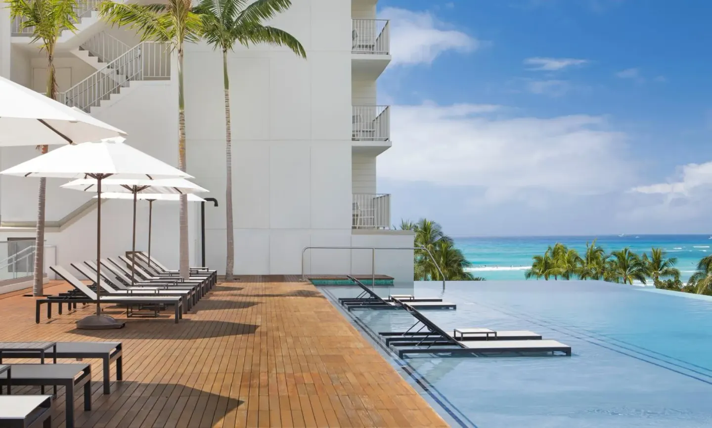 Pool deck with umbrellas and ocean view at 'Alohilani Resort Waikiki Beach.