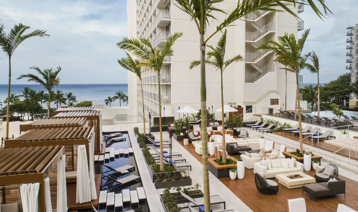 Pool deck with cabanas, loungers, and ocean view at 'Alohilani Resort Waikiki Beach.