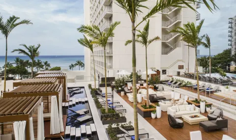 Pool deck with cabanas, loungers, and ocean view at 'Alohilani Resort Waikiki Beach.