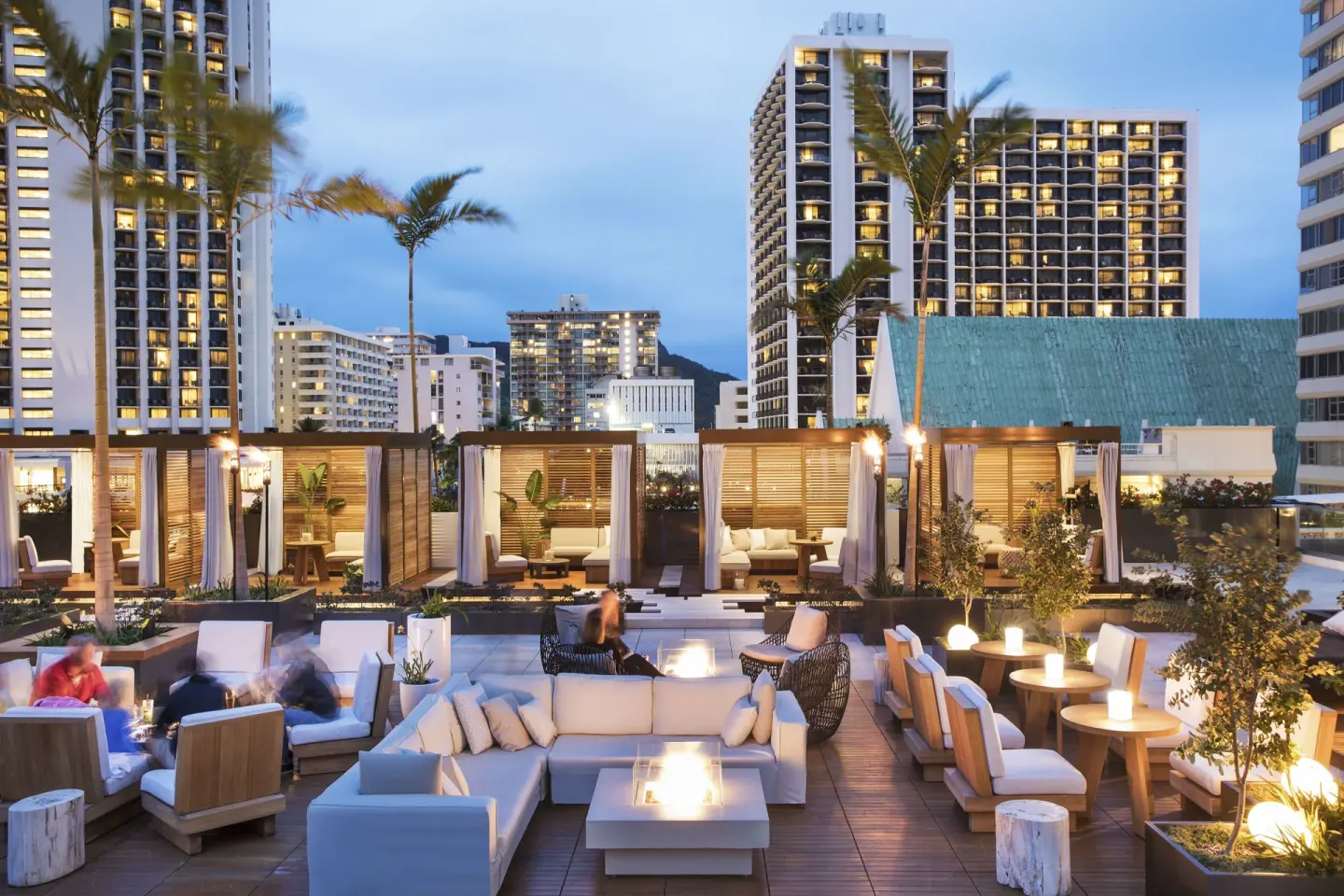 Rooftop lounge seating and cabanas at twilight at 'Alohilani Resort Waikiki Beach.