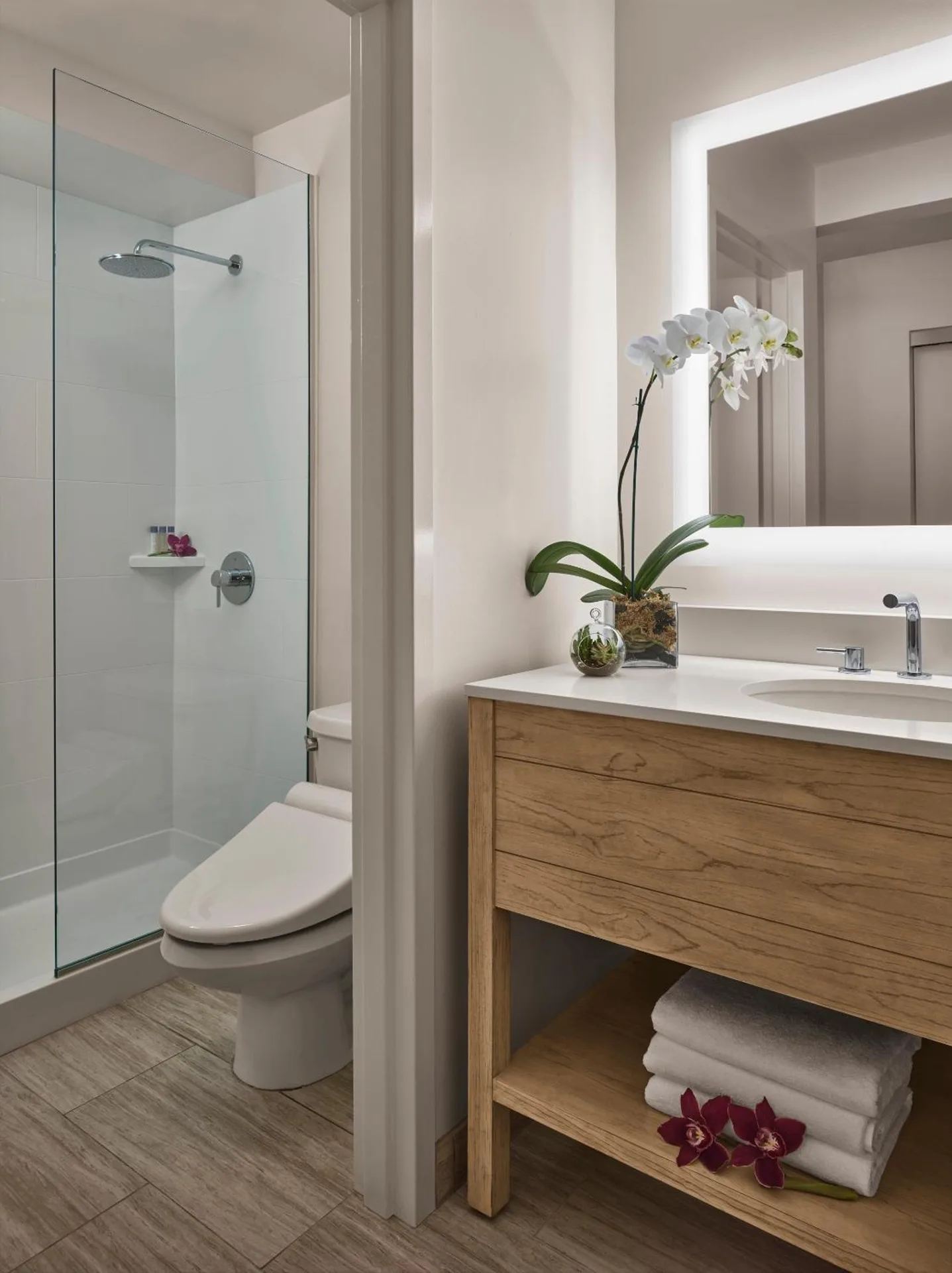Bathroom vanity and glass shower in a Classic 2 Queens room at 'Alohilani Resort Waikiki Beach.