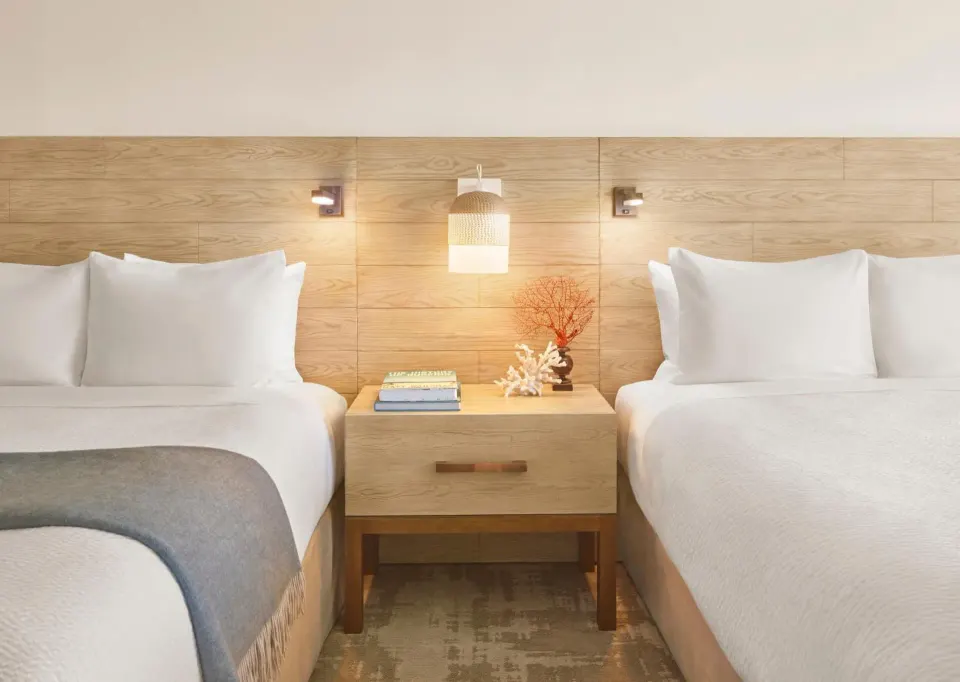Two queen beds with white linens in a Classic 2 Queens room at 'Alohilani Resort Waikiki Beach.