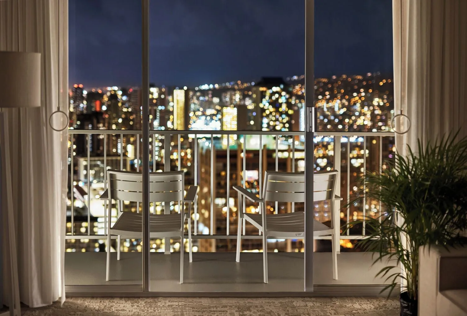 Classic Room balcony chairs with night city view at 'Alohilani Resort Waikiki Beach.