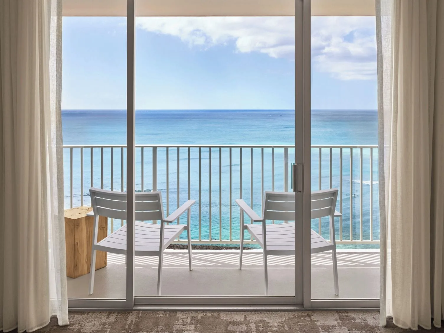 Oceanfront balcony view with two chairs outside a guest room at 'Alohilani Resort Waikiki Beach.