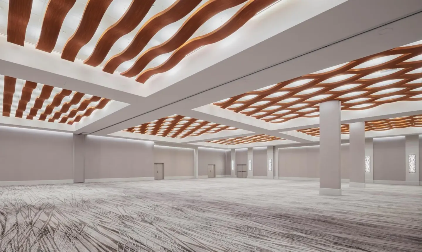 Empty ballroom with wave-pattern ceiling panels at 'Alohilani Resort Waikiki Beach.