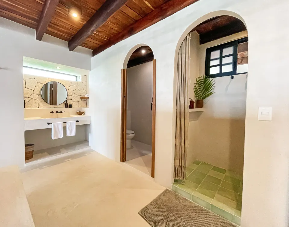 Bright bathroom with arched doorways, shower and round mirror at Amansala