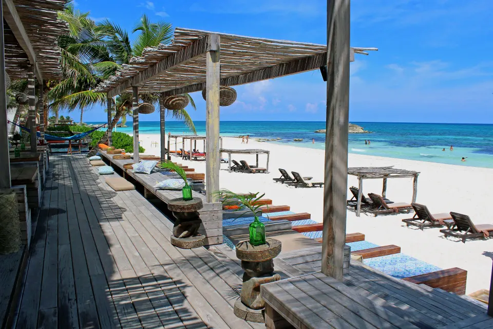 Shaded wooden deck and lounge beds on the white sand beach at Amansala
