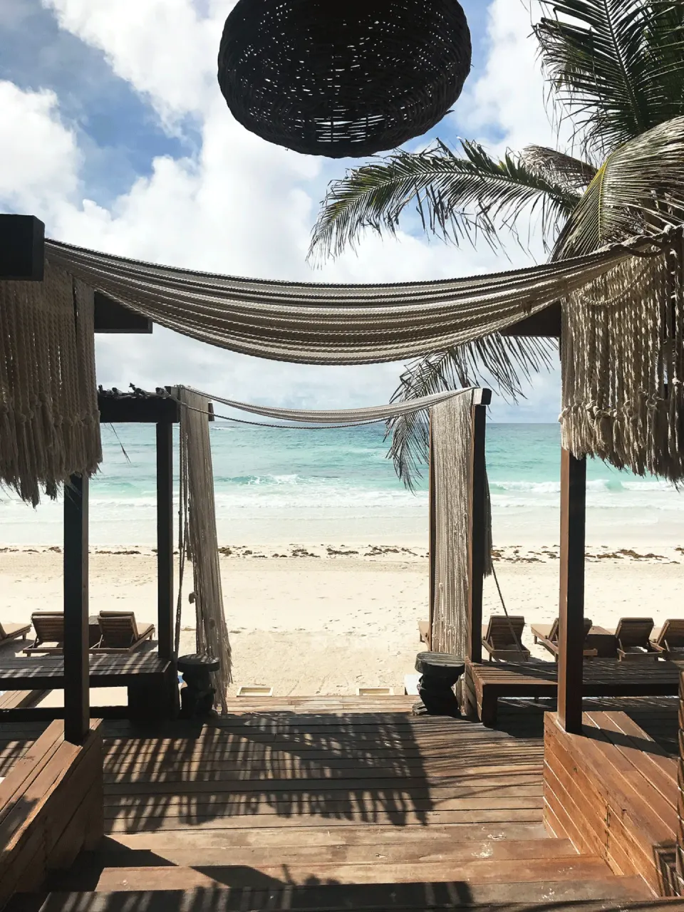 Wooden cabana walkway opening onto the sandy beach and turquoise sea at Amansala