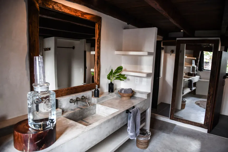 Concrete sink with large mirror and open shelving in a bathroom at Amansala