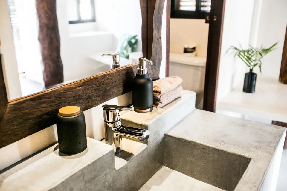 Concrete sink and countertop with toiletry bottles in a bathroom at Amansala