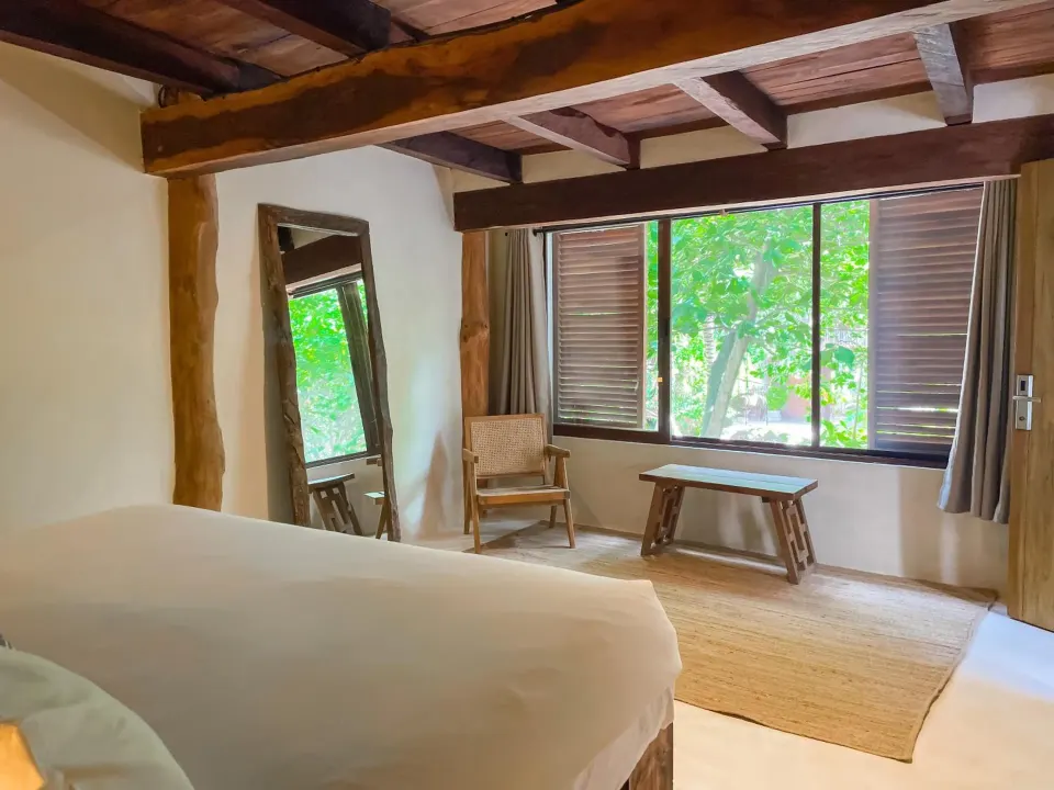 Light-filled guest room with king bed and window view of tropical foliage at Amansala