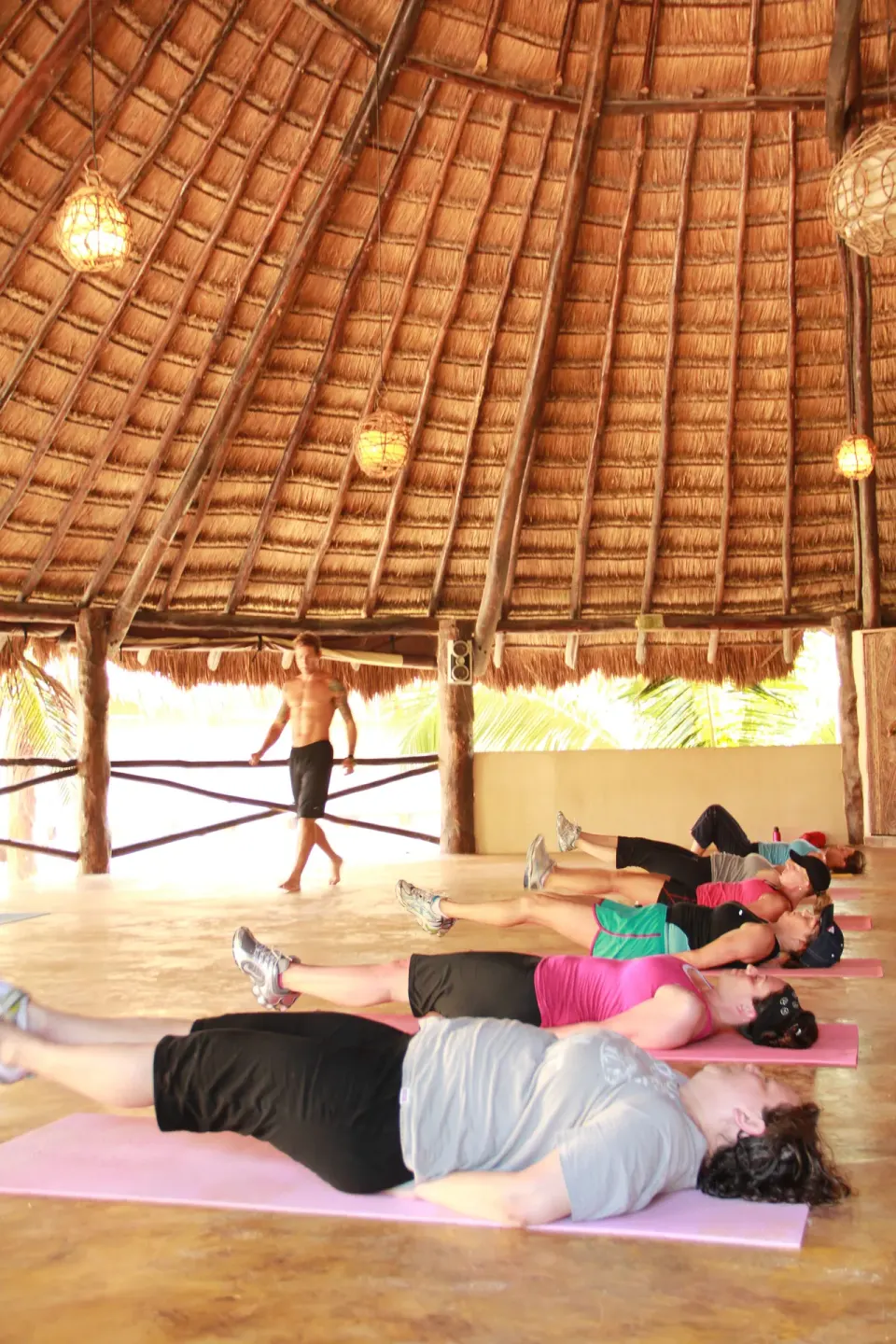 Fitness class doing floor exercises in a thatched palapa at Amansala