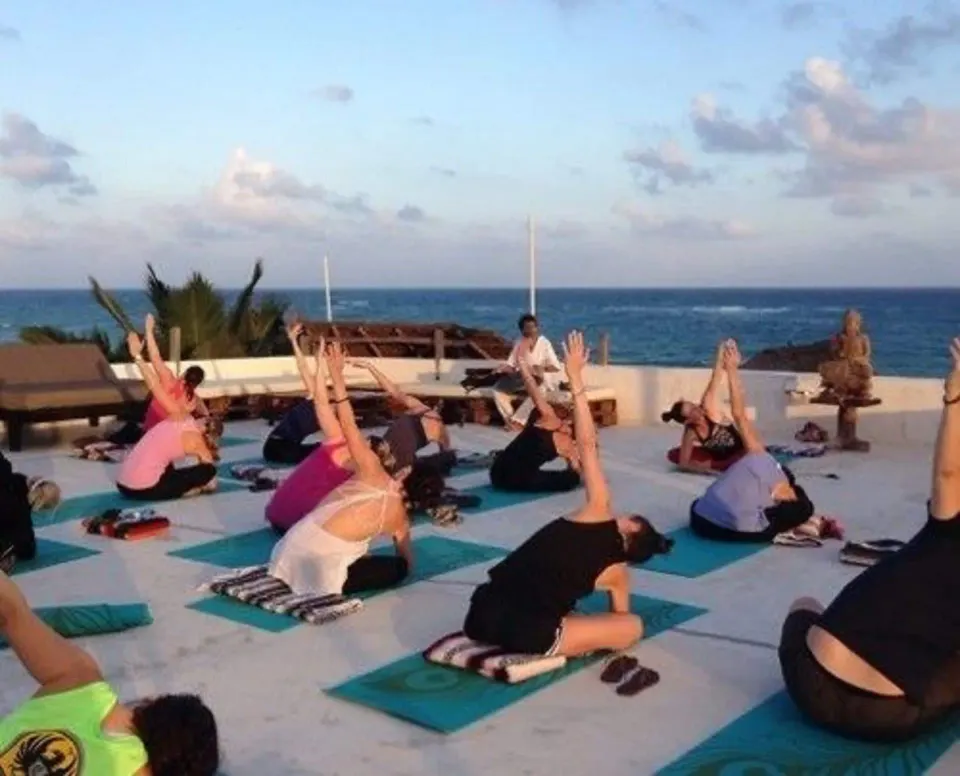 Group yoga class practicing on mats on an oceanfront deck at Amansala