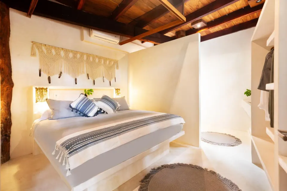 King bed with textured throws and exposed wood beams in a guest room at Amansala