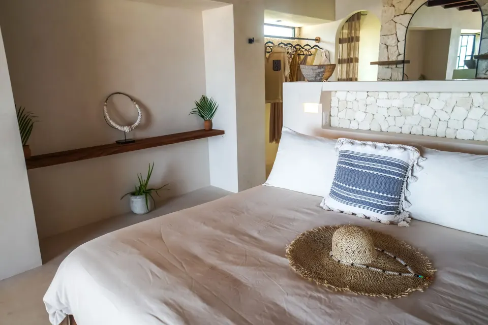 Neutral-toned king bed with woven hat and shelf accents at Amansala