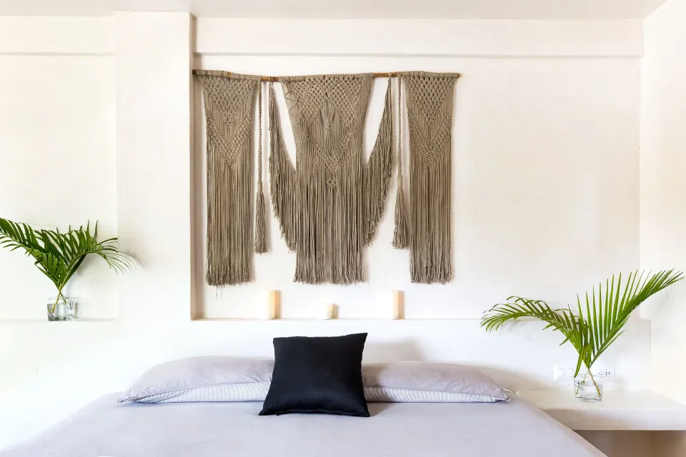 Minimal bed with macramé wall art and palm fronds at Amansala