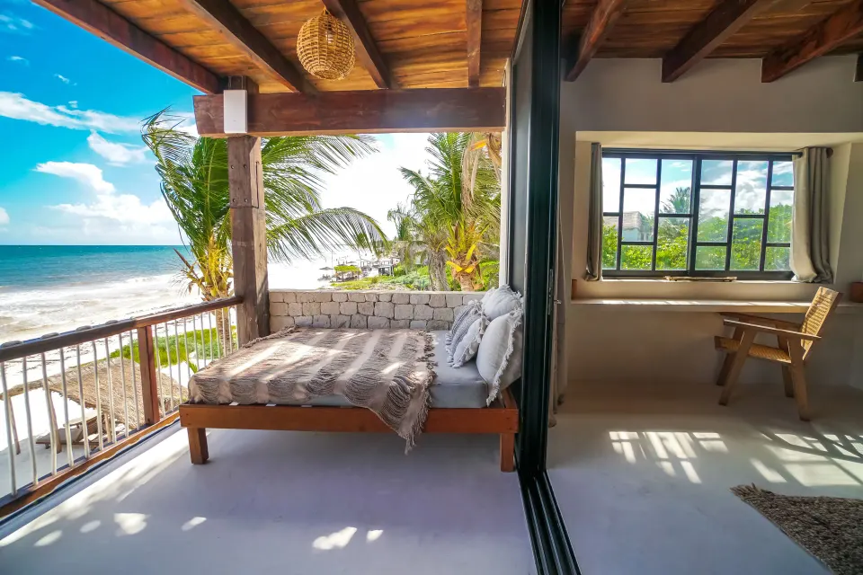 Ocean-facing daybed and balcony view at Amansala resort with palms and waves