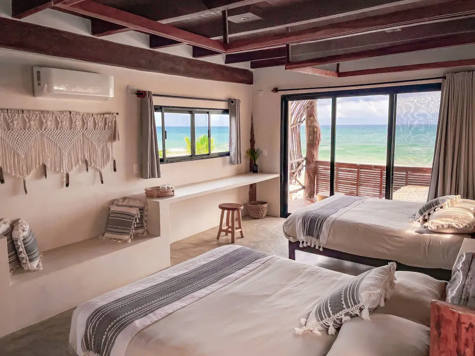 Seaside twin beds with sliding balcony doors and woven wall hangings at Amansala