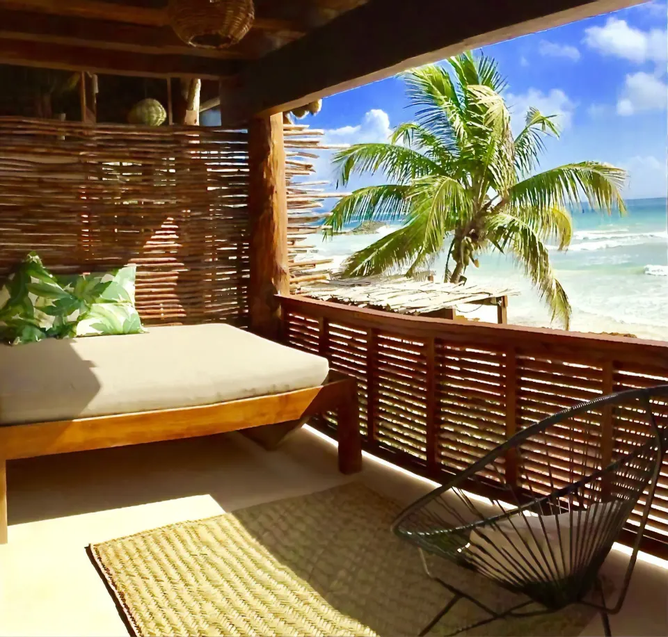 Shaded wooden terrace with daybed and ocean view at Amansala