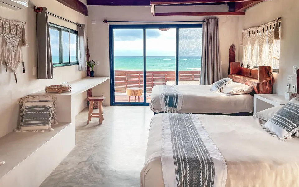 Twin beds in a bright room with sliding doors to an ocean balcony at Amansala