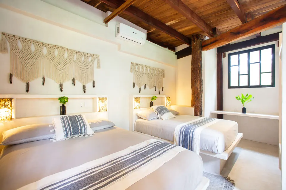 Twin beds with matching linens and macramé wall hangings at Amansala
