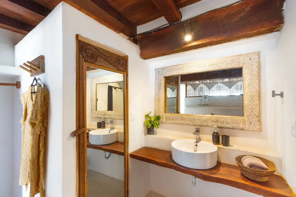 Dual vessel sinks and carved wooden mirror on a wooden counter at Amansala