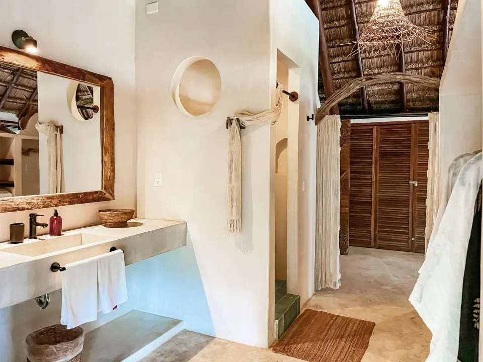 Bright walk-through bathroom with dual sink and thatched ceiling at Amansala