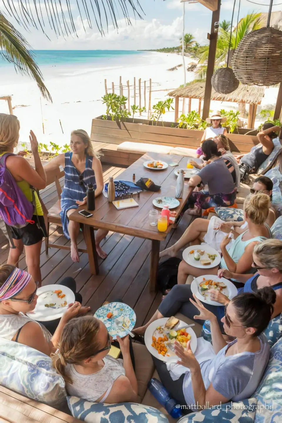 Groups dining on a wooden deck overlooking the beach at Amansala
