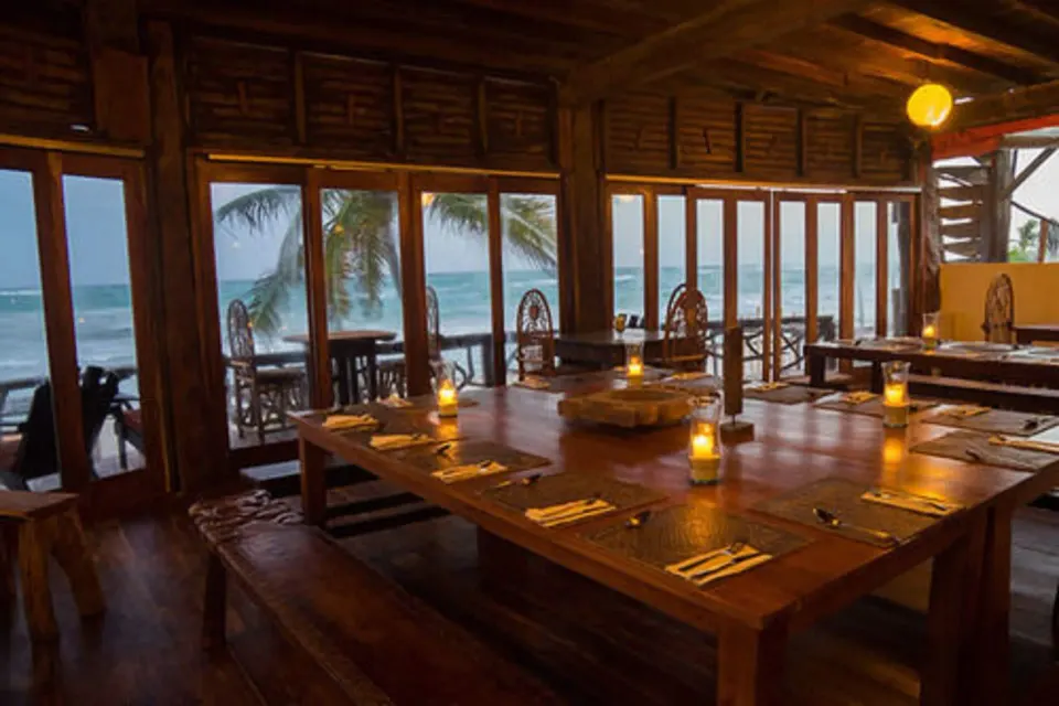 Candlelit wooden dining room with ocean view through sliding doors at Amansala