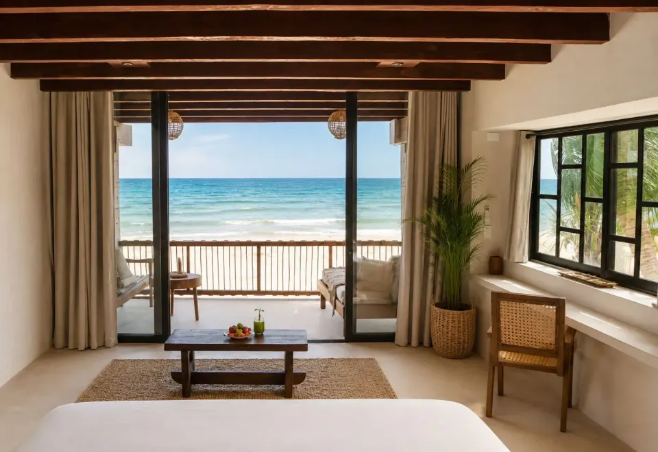 Spacious beachfront room with sliding doors to balcony and ocean beyond at Amansala