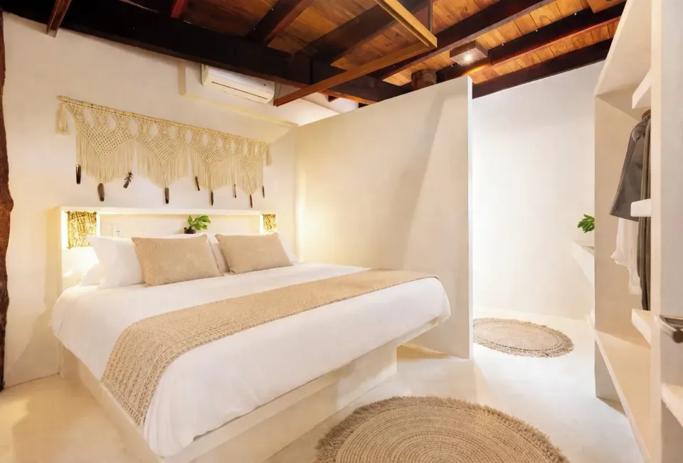 King bed beside curved shower entry and woven rugs in Town House Shanti at Amansala