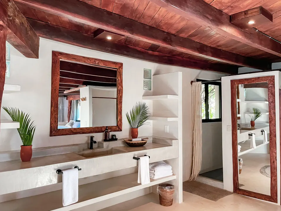 Triple Room at Amansala double vanity with wooden-framed mirror and countertop sink under exposed beams